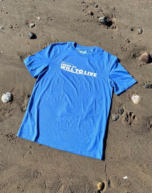 blue t-shirt on the beach surrounded by seashells; graphic print saying "finding my will to live"