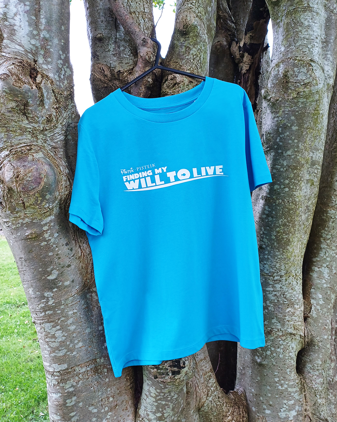 Blue parody graphic T-shirt hung on a tree, with "Finding my will to live" printed on it - by PISTEIK